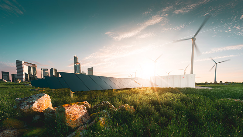 Im Vordergrund stehen Windräder und Photovoltaikanlagen. Im Hintergrund liegt eine Stadt.