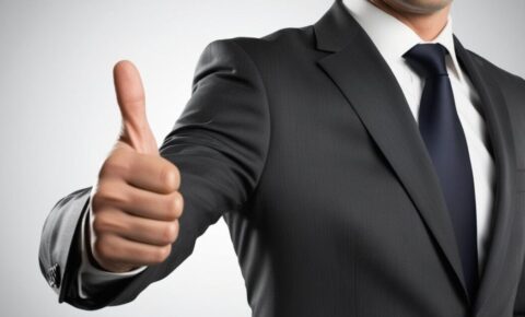 Geschäftsmann im dunklen Anzug und blauer Krawatte zeigt Daumen hoch
