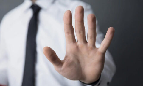 Mann im weißen Hemd zeigt offene Hand mit fünf Fingern