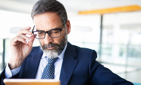 Nachdenklicher Geschäftsmann im Anzug liest Dokument zur betrieblichen Altersvorsorge